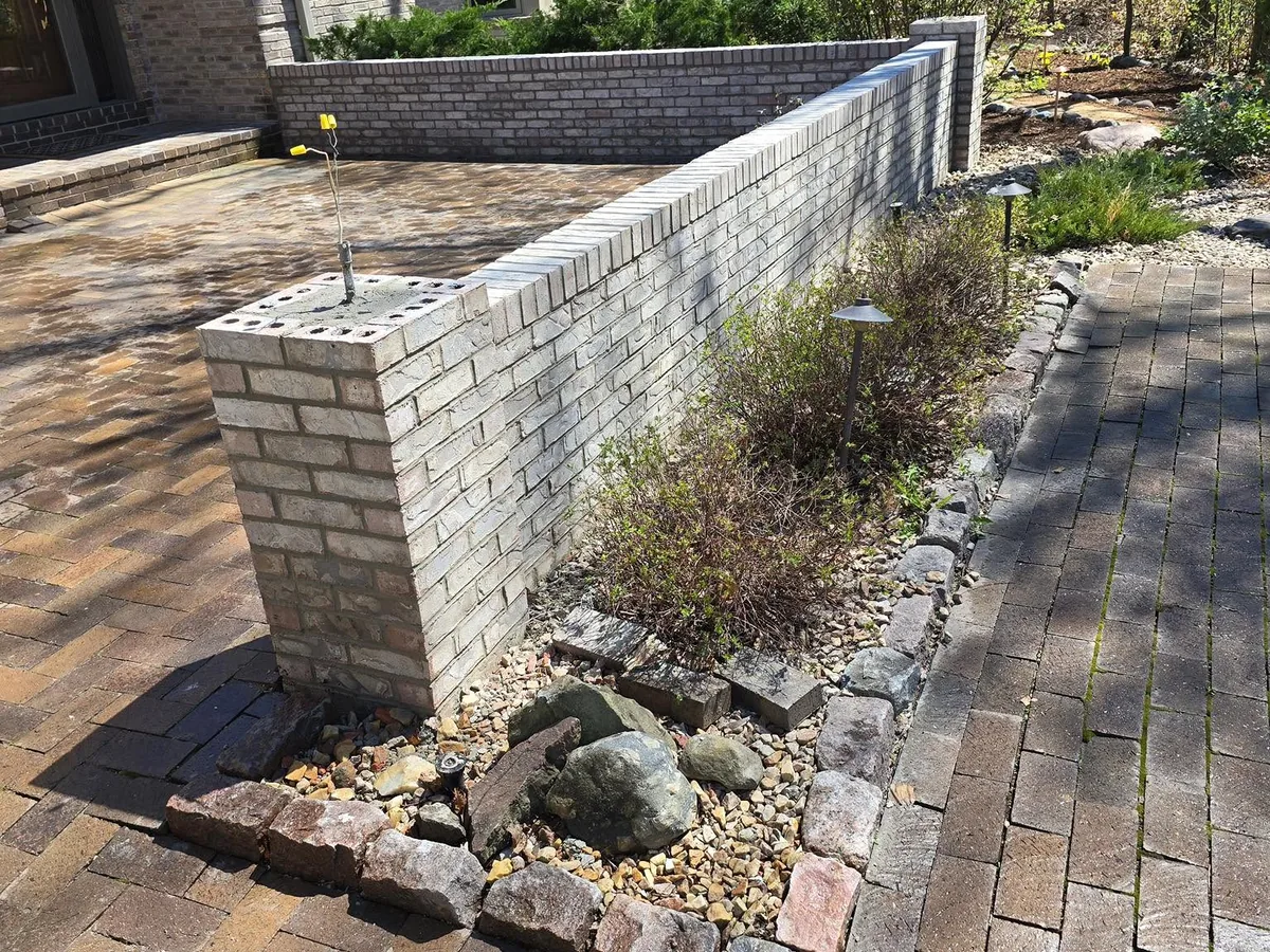 Light brick garden wall bordering a paver patio and landscaping