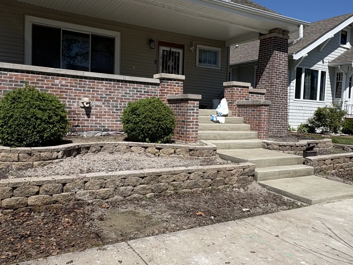Brick home entry with stacked stone retaining walls flanking the concrete steps