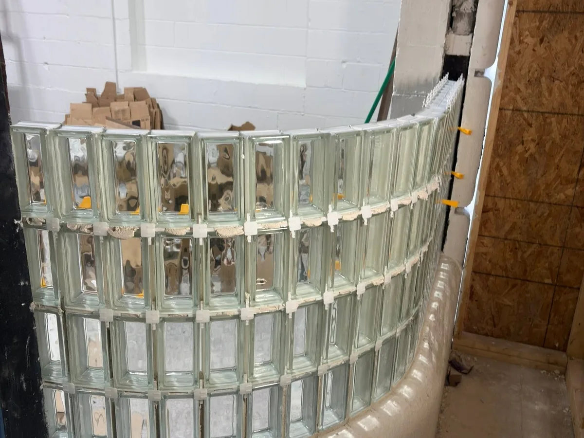 Curved interior glass block wall under construction against exposed wall framing