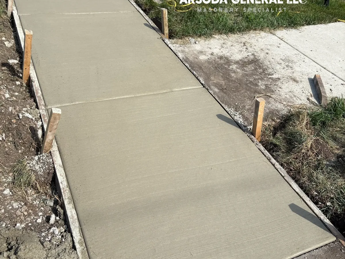 Freshly finished concrete walkway still framed by wood forms