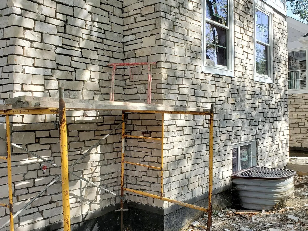 Light cut stone veneer being installed on a home exterior with scaffolding in place